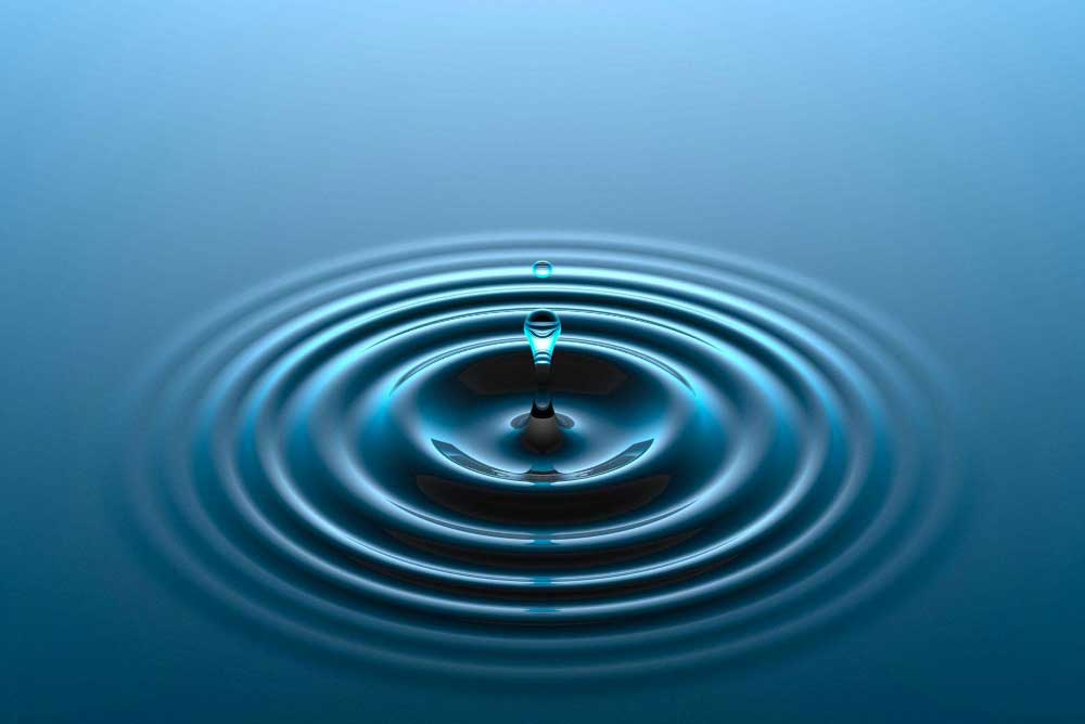 A single water droplet creating expanding ripples, representing sustained impact
